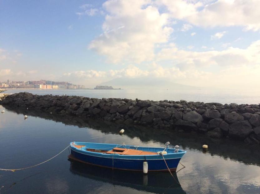 A local boat in the Porto di Napoli, with the active volcano Mount Vesuvias visible in the background.